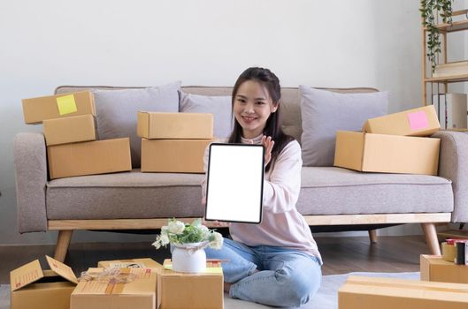 Portrait of Starting small Asian young businesses owners showing tablet with blank screen at home.