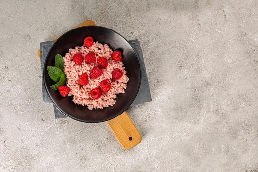 Healthy food on gray concrete background. Fresh raspberries risotto on a delicate and elegant dish