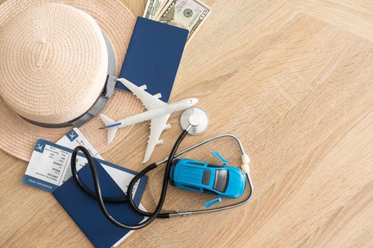 Travel and healthcare concept. Top view of passport, stethoscope and toy plane on wooden background with copy space