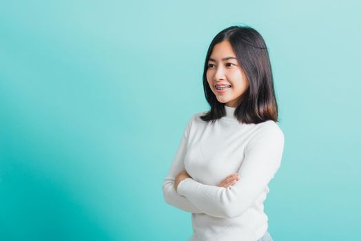 Young beautiful Asian woman smiling with crossed arms, Portrait of positive confident female stand cross one's arm, studio shot isolated on a blue background
