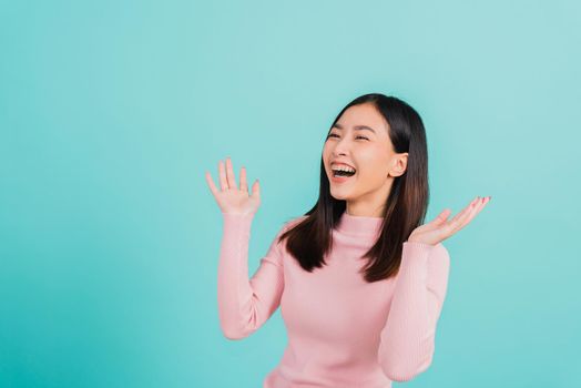 Happy young Asian beautiful woman smiling wear silicone orthodontic retainers on teeth surprised she is excited screaming and raise hand make gestures wow, studio shot isolated on blue background