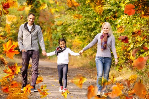 family walking in an autumn park with fallen fall leaves. High quality photo