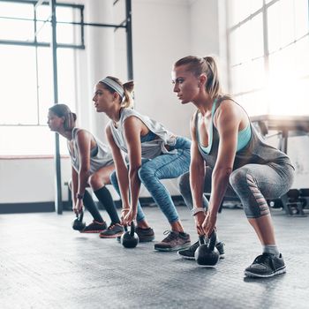 You have the strength to be powerful. three women working out with weights at the gym