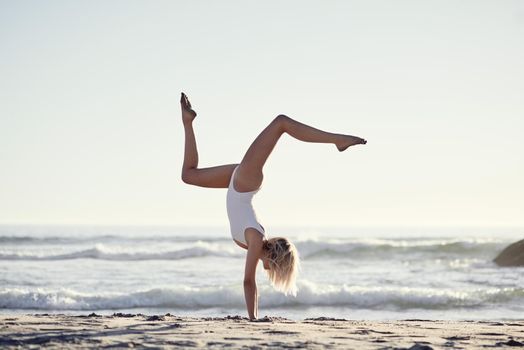 Life is just simpler at the beach. Full length shot of a young woman doing a handstand on the beach