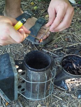 starting a bee smoker before harvesting honey hives in the farm.