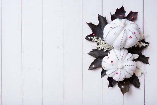 Creative autumn flat lay composition with white textile decorative pumpkins and dark mapl leaves top view decorated with rhinestones. Copy space