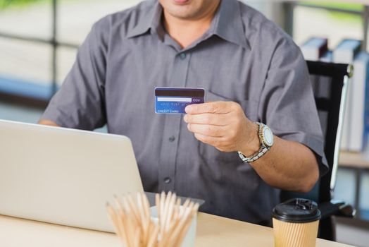 Closeup Asian senior adult man holding credit card and using technology on laptop computer, Online shopping payment with a customer network connection via an Omnichannel system