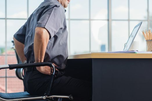 Asian hard senior businessman working with laptop computer has a problem with back pain. Old man feeling pain after sitting at desk long time, Healthcare and medicine office syndrome concept