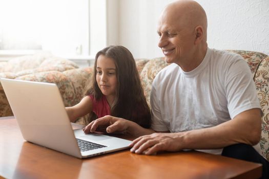 Grandfather adult granddaughter spend time together use laptop, browse website, younger generation teach explain to older how to use modern tech concept.