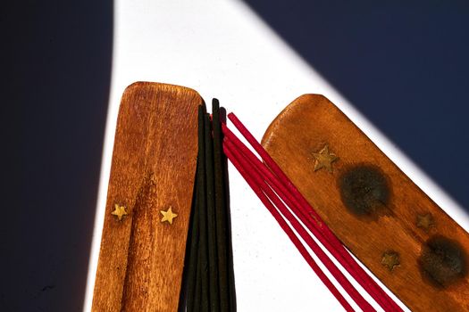 a gum, spice, or other substance that is burned for the sweet smell it produces. Red black incense sticks and wood stand. Meditation,calm.