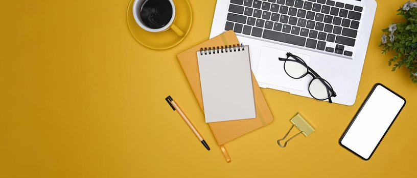 Top view stylish workplace with laptop computer, mobile phone, notebooks and coffee cup.