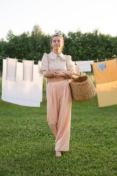 Laundry day. A woman hangs linen and towels on a tree in the courtyard of a village house. Summer cottage concept.