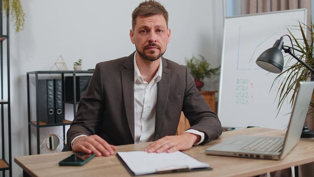 Stressed businessman in formal wear suit feeling worried about financial problem doing paperwork at office. Concentrated male freelancer man frustrated thinking of money debt, budget loss, bankruptcy