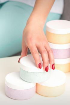 Beautician's hand takes jar with cosmetics from table offering and selling cosmetic products, moisturizing cream, wax paste