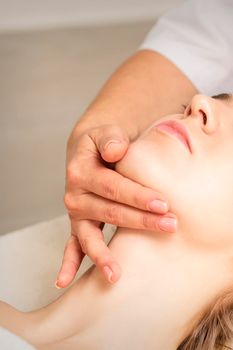 Young caucasian woman receiving a head and chin massage in a spa medical center