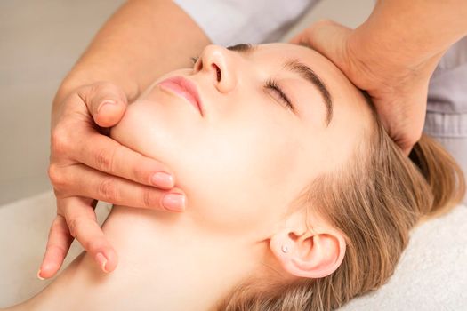 Young caucasian woman receiving a head and chin massage in a spa medical center