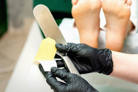The pedicure master putting on new sandpaper on the metal handle before the procedure of cleaning the foot and heel in a nail salon