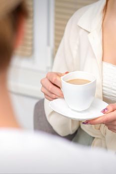 Young caucasian unrecognizable woman holding a cup of hot drink at a doctor's appointment in hospital office