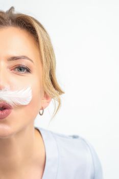 Funny beautician with a white feather-like mustache poses on white background, depilation concept