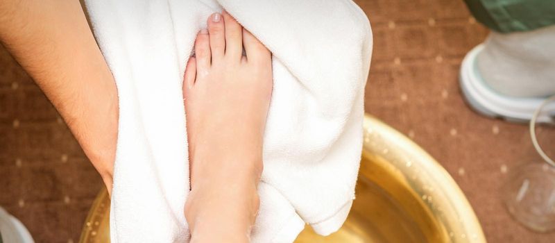Top view close up of male therapist drying leg of a white woman with a towel after washing in a spa beauty salon