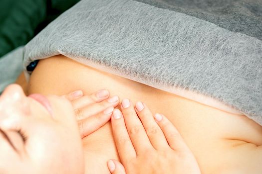Masseuse makes a chest massage of a young caucasian woman in a spa salon