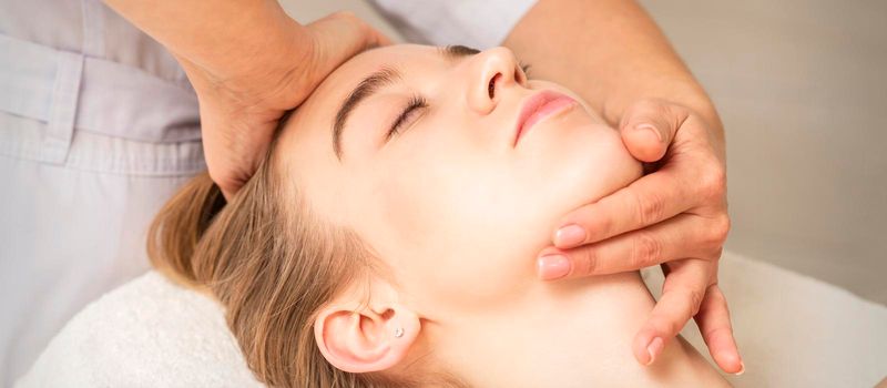 Young caucasian woman receiving a head and chin massage in a spa medical center