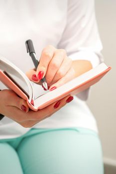 Close up of female doctor therapist writes notes in a medical notepad sitting in medical office