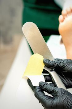 The pedicure master putting on new sandpaper on the metal handle before the procedure of cleaning the foot and heel in a nail salon
