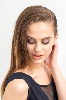 Beautiful young caucasian woman with natural makeup smiling and looking down standing on white background