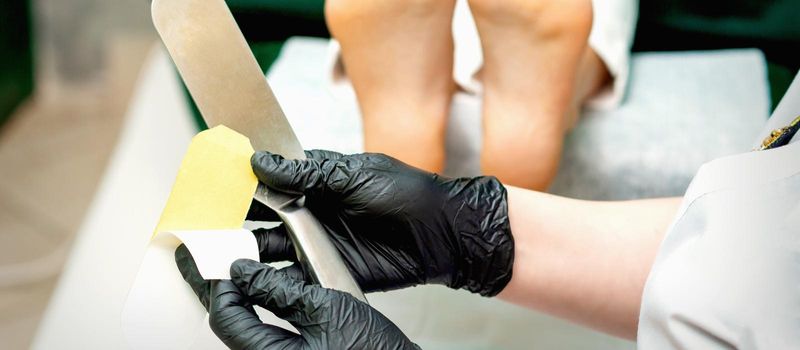 The pedicure master putting on new sandpaper on the metal handle before the procedure of cleaning the foot and heel in a nail salon