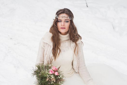 Beautiful bride in a white dress with a bouquet in a snow-covered winter forest. Portrait of the bride in nature.Beautiful bride in a white dress with a bouquet in a snow-covered winter forest. Portrait of the bride in nature.
