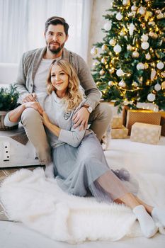 A happy couple in love - a man and a woman. A family in a bright New Year's interior with a Christmas tree.