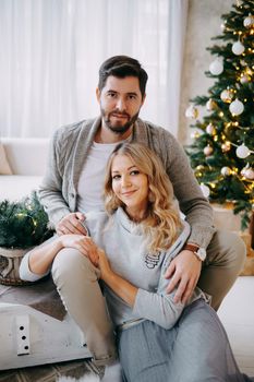 A happy couple in love - a man and a woman. A family in a bright New Year's interior with a Christmas tree.