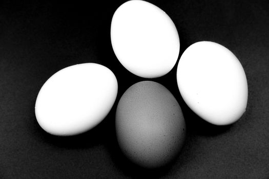 Brown and three white eggs on the table