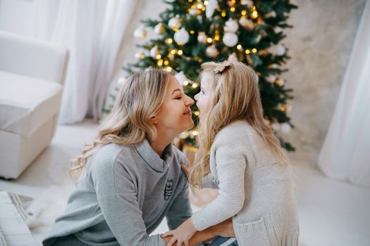 Happy family: mother and daughter. Family in a bright New Year's interior with a Christmas tree.