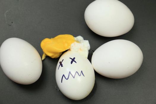 White eggs, one of them boiled and broken an simulating an accident