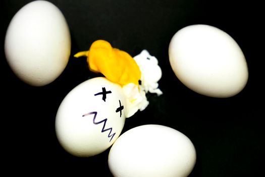 White eggs, one of them boiled and broken an simulating an accident