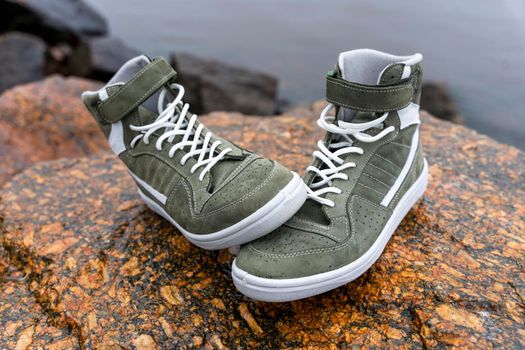 new fashionable high youth sneakers on a stone background on the bay shore. sports comfortable leather shoes. casual shoes