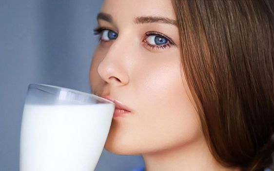 Happy young woman drinking milk or protein milk shake cocktail, healthy drink for diet and wellness concept