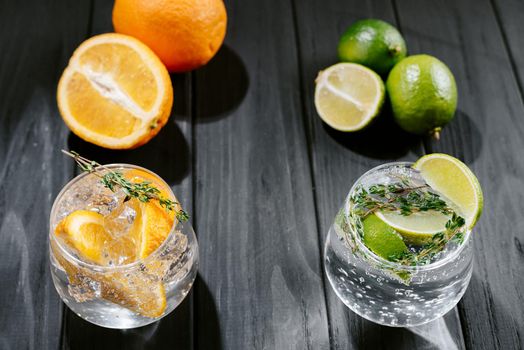 Lime lemonade with thyme, ginger and ice and orange. wooden dark background. Flashy food and drink. Healthy summer cocktails, mocktails. Set of different citrus lemonades mojitos, with lime, orange, diet detox drinks