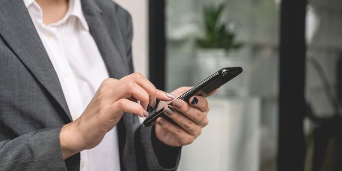 Close up of business woman using mobile smart phone.