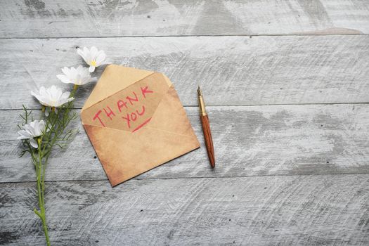 thank you message and envelope on wooden table.