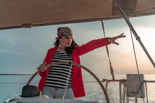 Attractive middle-aged woman at the helm of a yacht on a summer day. Luxury summer adventure, outdoor activities