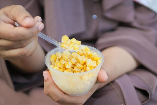 women holding a plastic bowl of organic sweet corn .