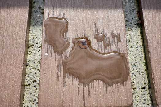 puddles of water on a bench after rain in a city park close-up
