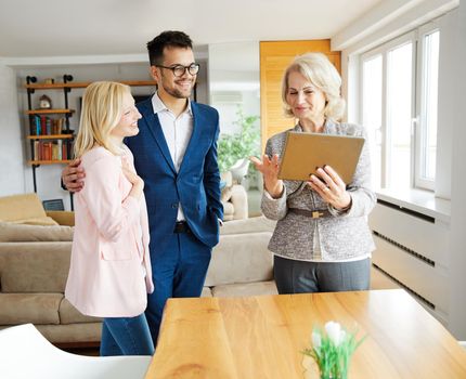 Young happy couple and an agent in a new property