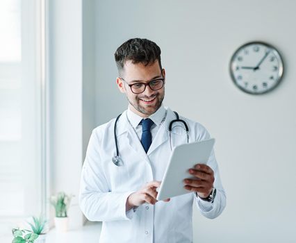 portrait of a young doctor holding a tablet computer in his office in a hospital