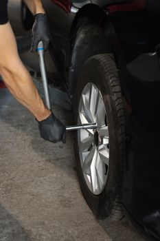 Repairman mounting wheel tire at service station. Car mechanic replacing a car wheel tire in garage workshop. Auto service.