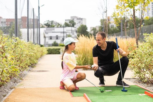 Family playing miniature golf outdoors.