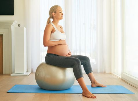 Staying healthy for a stress free pregnancy. a pregnant woman working out with an exercise ball at home